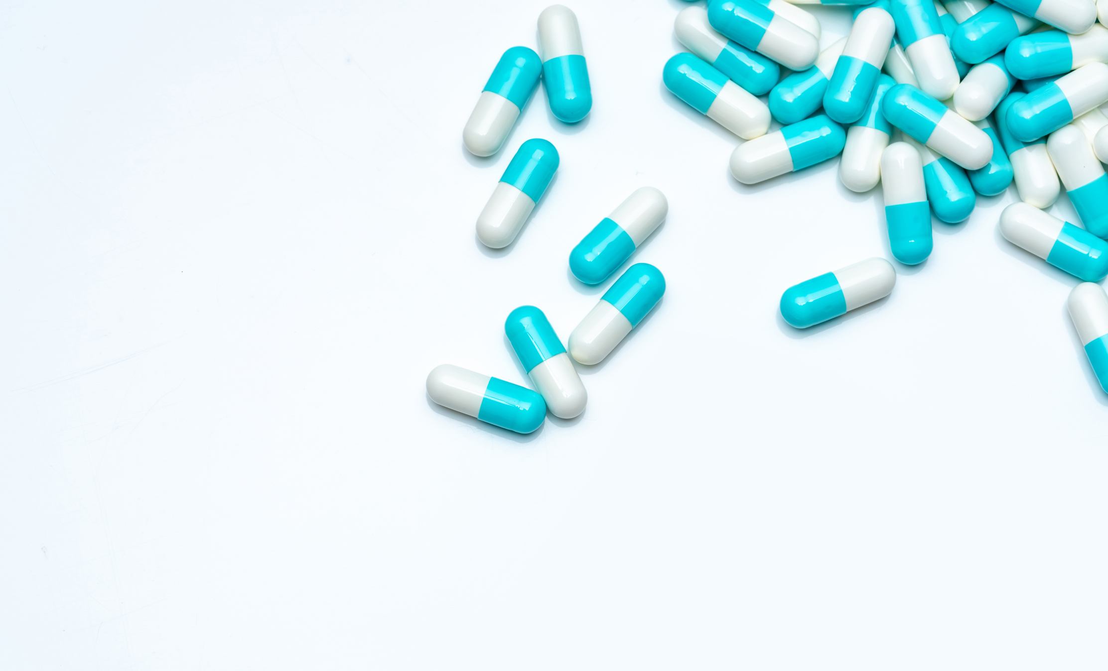 Blue-white capsule pills on white background. Antibiotic drug resistance concept. Capsule pills sampling in pharmaceutical industry. Antimicrobail medicine. Pharmacy product. Medication for infection.