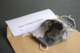 Notice to tenant for eviction inside brown envelope and face mask on top.