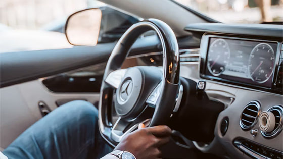 man in white dress shirt driving a car during the day; image used for blog post about tax depreciation rules for business automobiles