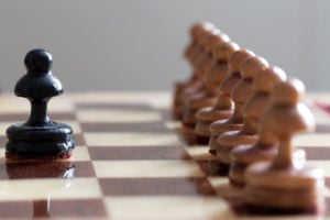 One chess piece facing a line of others representing New Brandeisian push for antitrust laws