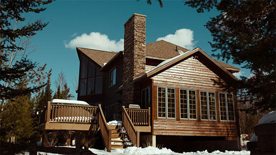 a wooden house in a snow-covered area of the woods; image used for blog post about tax consequences of renting out a vacation home