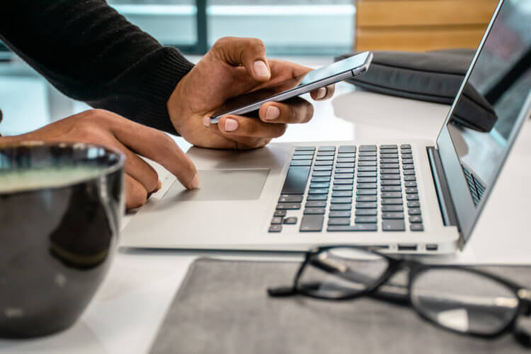 A legal professional holding a phone and typing on the laptop A legal professional holding a phone and typing on the laptop