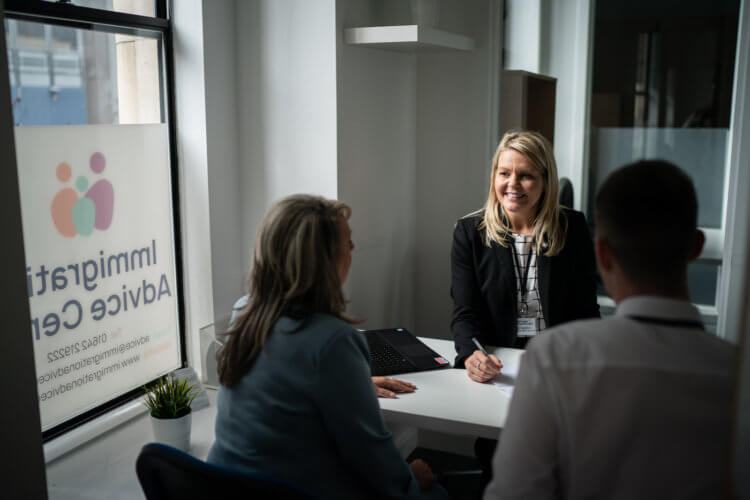 A photo of a lawyer working with two clients at a table in an office. A photo of a lawyer working with two clients at a table in an office.