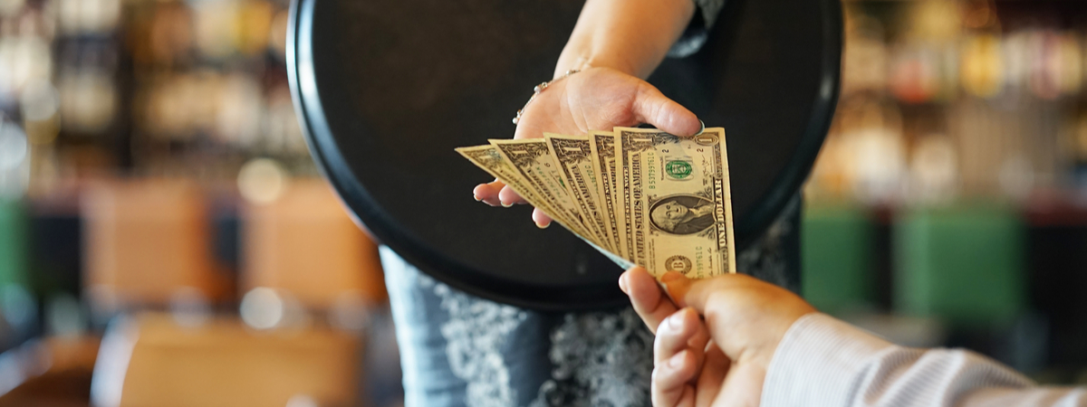 The hand of the waitress takes the tip. -shutterstock_1131971006 (1)