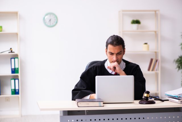 Well-dressed man sitting at desk with laptop, attending virtual court.