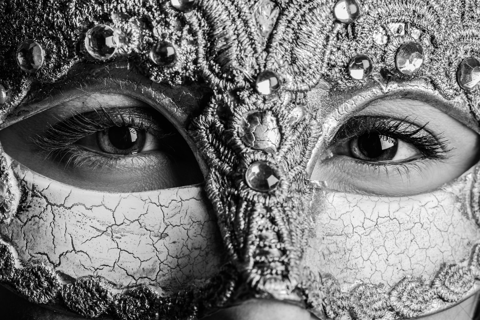 A womanpeers out to the camera from behind a Mardi Gras mask.