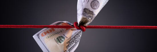 American dollar tied up in red rope knot on dark background with copy space. business finances, savings and bankruptcy concept.