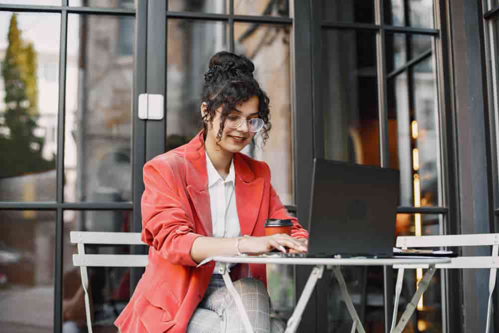 Women Entrepreneurship in Social Media General indian woman working laptop street cafe wearing stylish smart clothes jacket glasses min - Women Entrepreneurship in Social Media in General