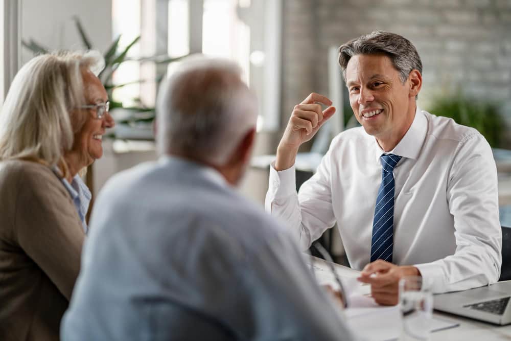 Sue Someone Commercial and Business Law happy insurance agent talking with mature couple about their retirement plans during meeting office min - Sue Someone in Commercial and Business Law