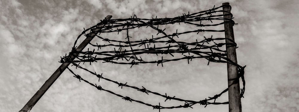 horizontal banner header with barbed wire concrete fence concept imprisonment deportation commemoration victims holocaust min - Refugee Deportation in the EU in General