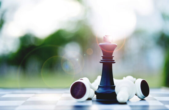 Black chess king among lying down white pawns