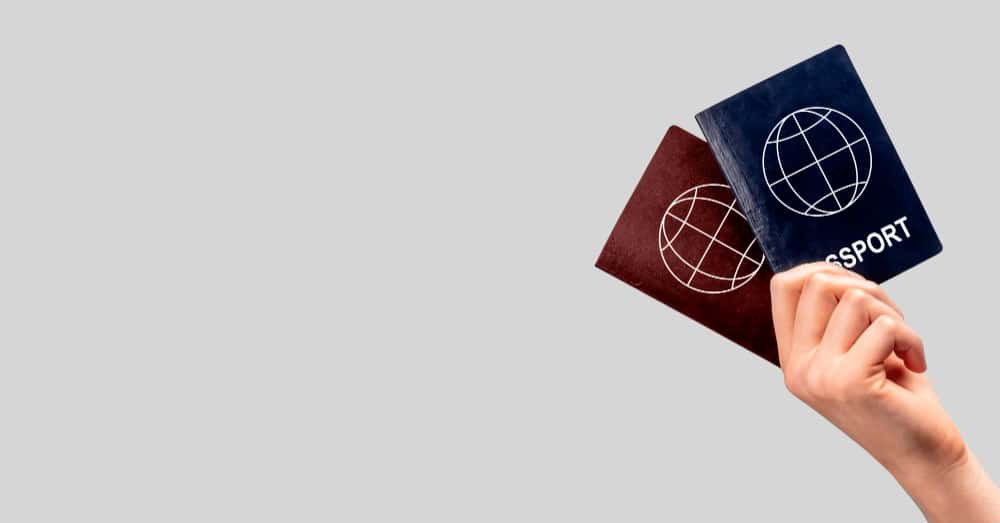 Dual nationality and conflict of laws General banner with woman hand holding two passports multiple dual nationality change citizenship residency status copy space grey background min - Dual nationality and conflict of laws in General