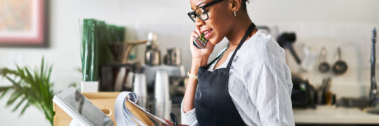 friendly waitress taking order on phone at restaurant and writing on notepad
