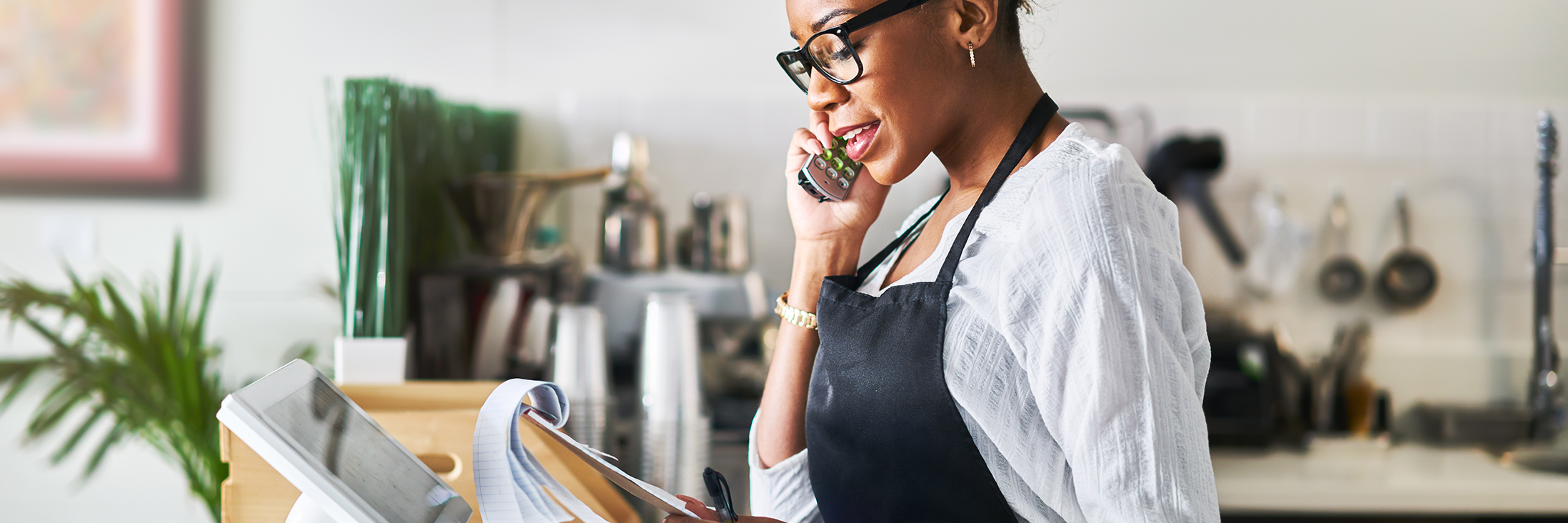 friendly waitress taking order on phone at restaurant and writing on notepad
