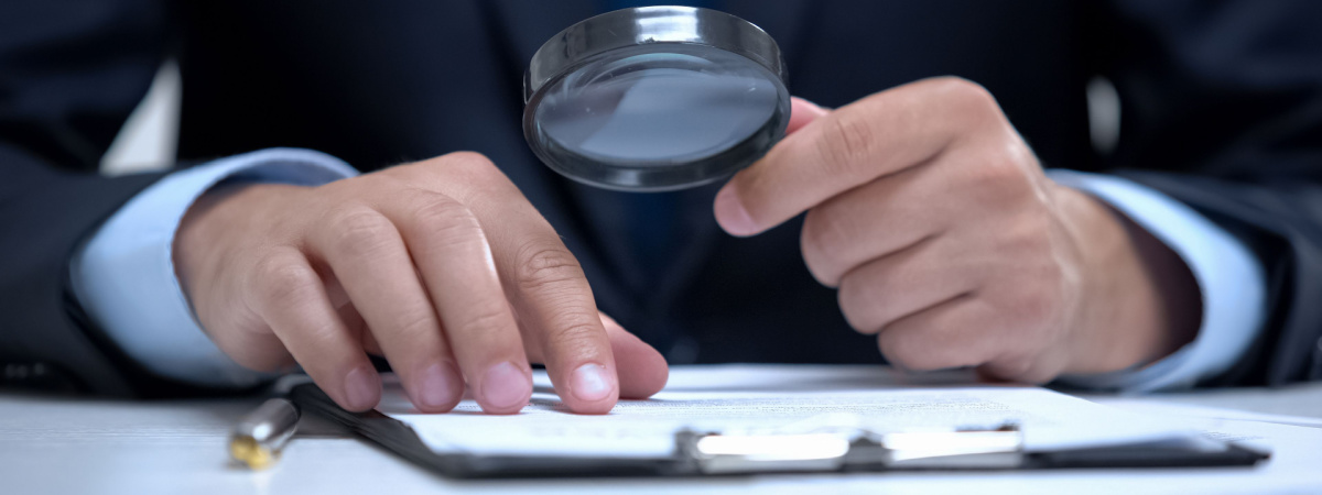 Attorney reading document with magnifier, studying case in detail, investigation-Shutterstock_1539656501