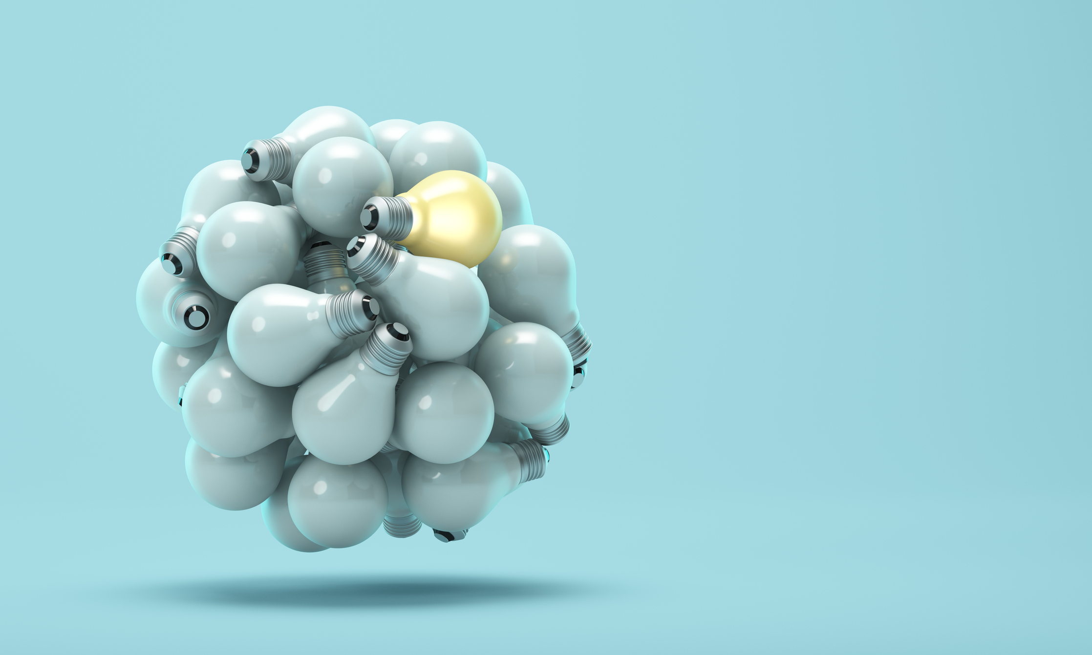 One glowing light bulb that stands out from unlit or dim lamps on a blue background