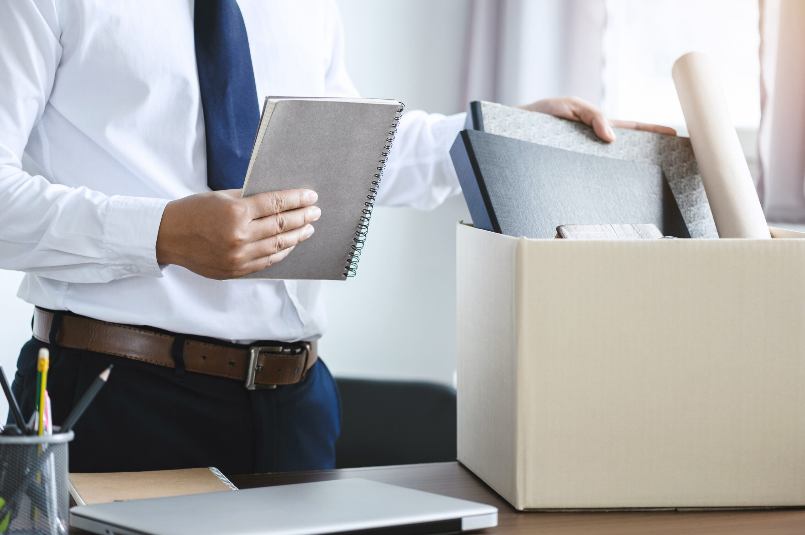 personnel packing personal belongings and files into a brown car