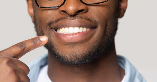 Closeup view african guy pointing finger to white toothy smile