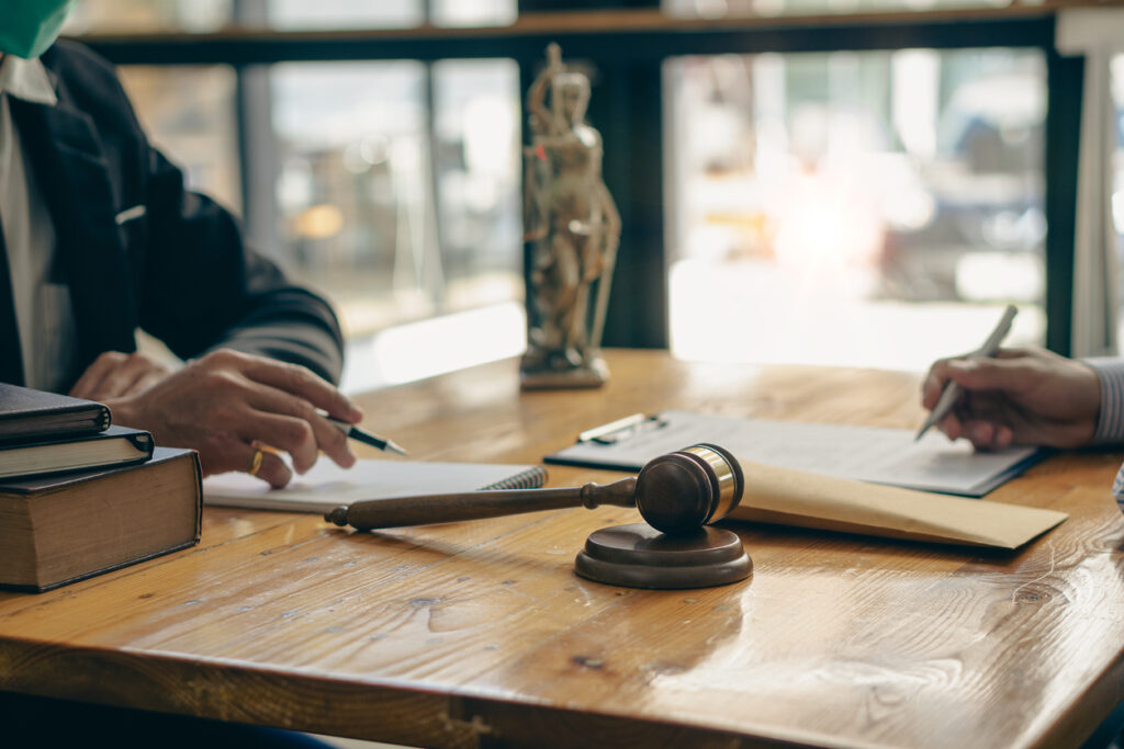 Lawyer working with client discussing contract documents with brass scales on law in courtroom Consulting to help clients win court cases