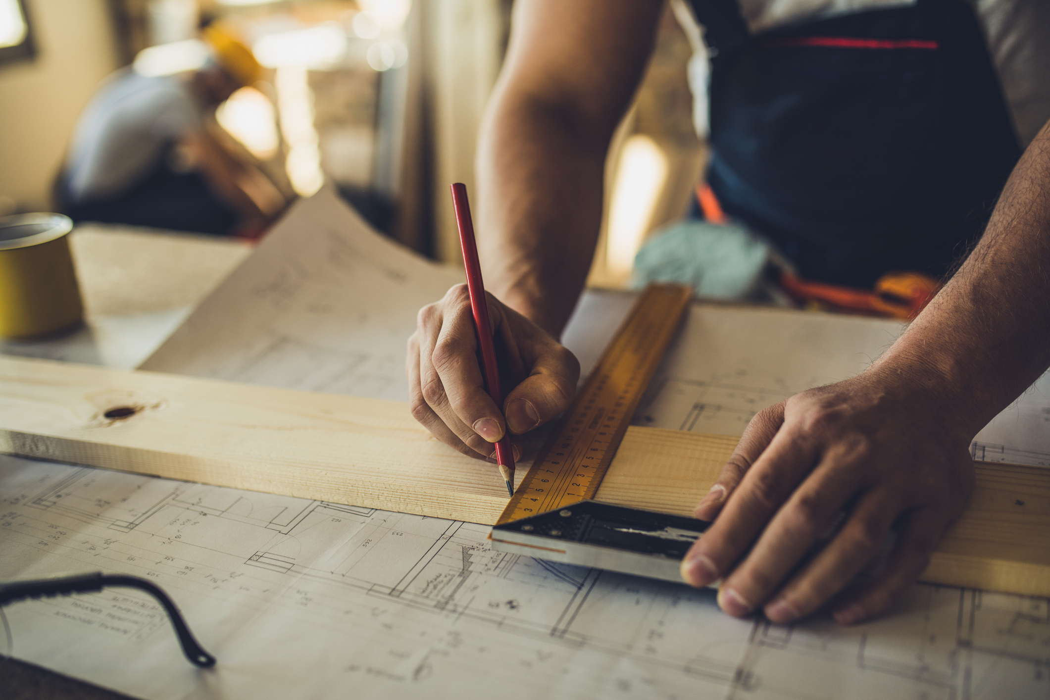 Close up of unrecognizable worker drawing on wood plank.