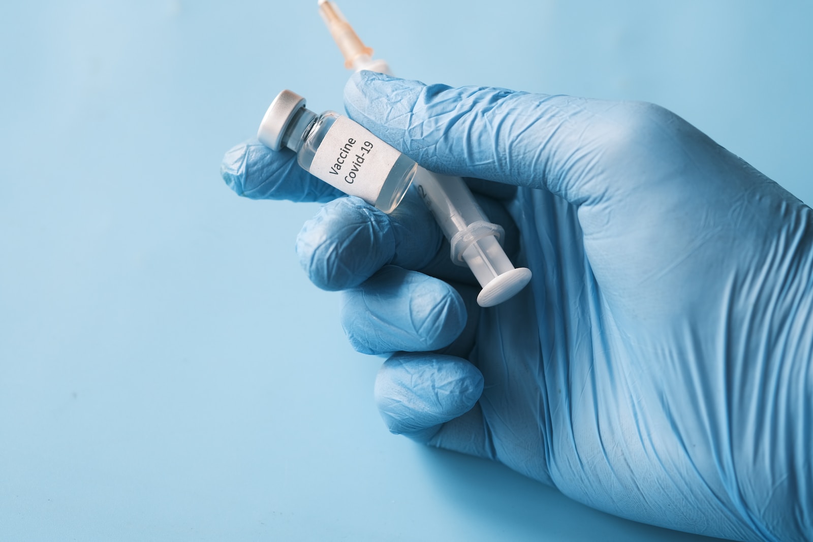 doctor hand in gloves holding coronavirus vaccine, close u.