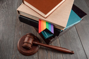 Judge's gavel and books with a rainbow bookmark on wood table. 