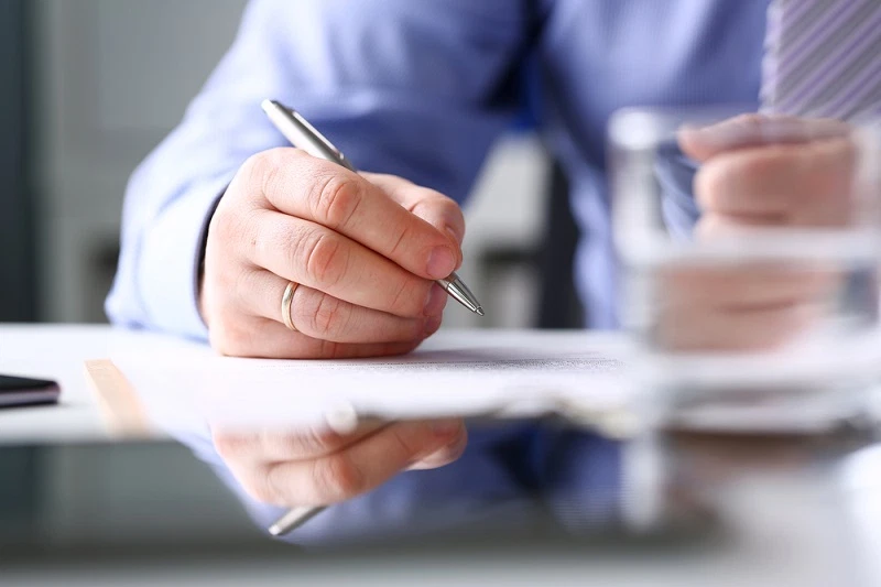 man signing a contract with a pen