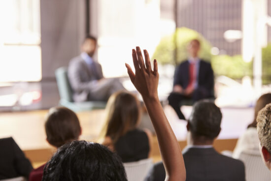Hand in audience raised for a question at a seminar