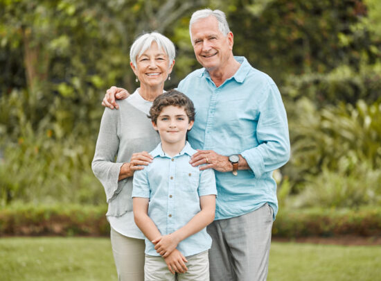 Our grandson is our shining star. a senior couple standing outside with their grandson.