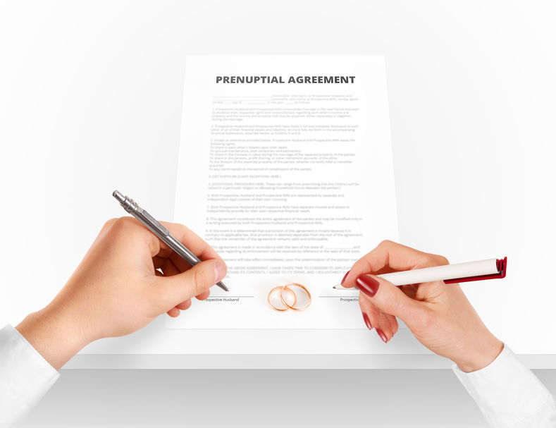 Man and woman sign prenuptial agreement near gold rings.