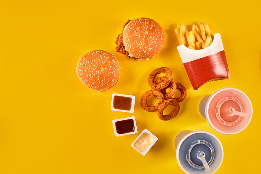 Fast food dish top view. Meat burger, potato chips and wedges. Take away composition. French fries, hamburger, mayonnaise and ketchup sauces on yellow background.