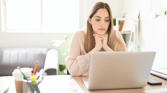 Picture of a woman working at a laptop in front of a window