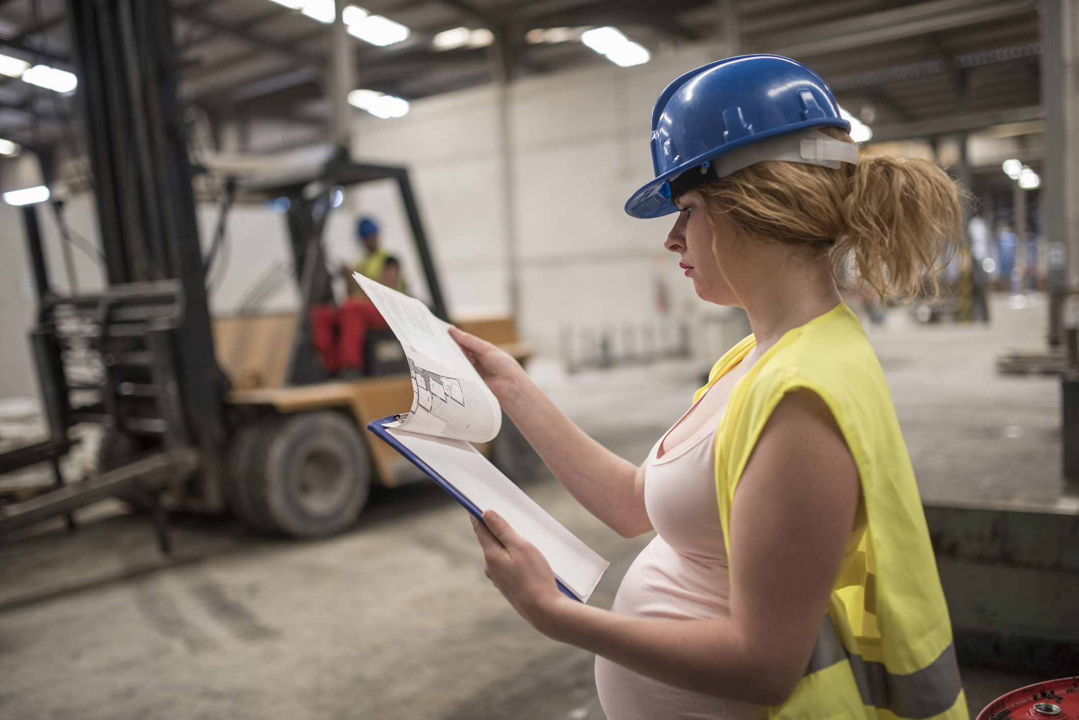 Pregnant worker woman in concrete factory looking note, looking at the work planning plan. Preparing labor