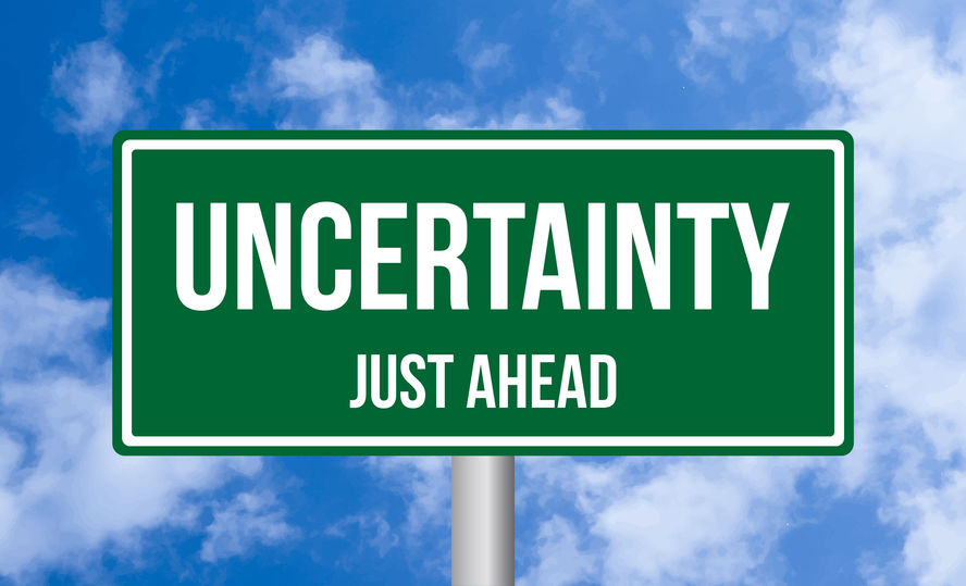 Uncertainty just ahead road sign on cloudy sky background
