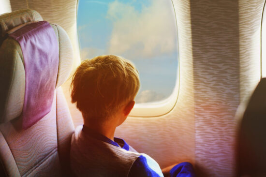 little boy travel by plane looking through window