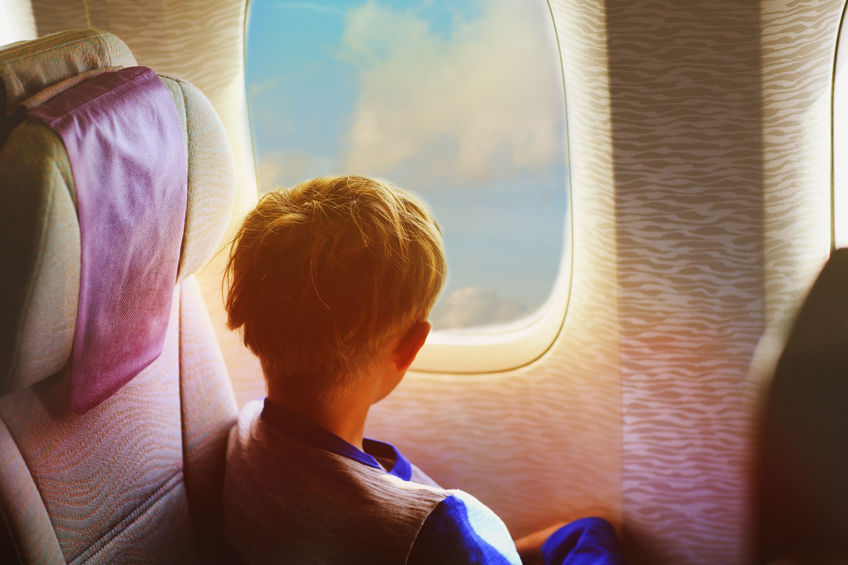 little boy travel by plane looking through window