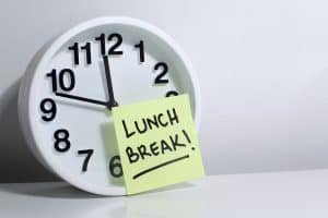 California Employees Are not Required to Waive their Meal Breaks 2 A clock pointng to 11:48 with a post-it note attached with "LUNCH BREAK!" written on it.