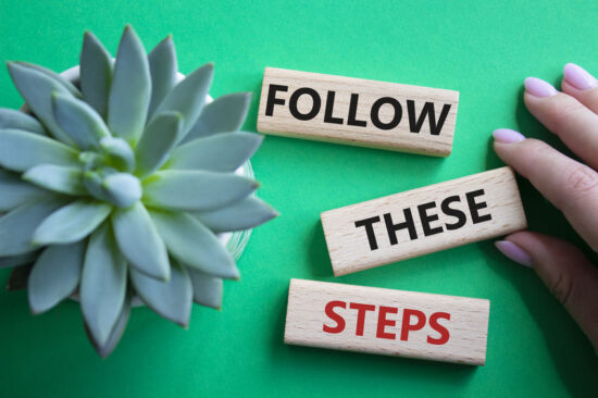 Follow these steps symbol. Wooden blocks with words Follow these steps. Beautiful green background with succulent plant. Businessman hand. Business and Follow these steps concept. Copy space.
