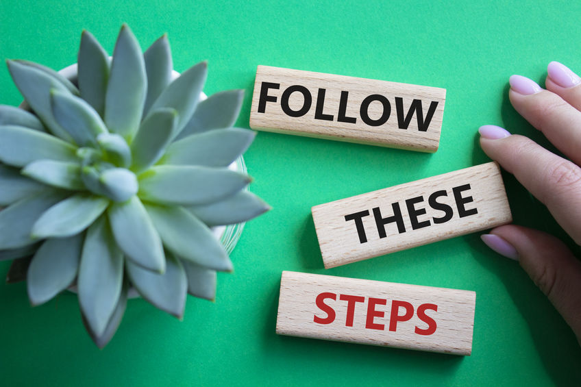 Follow these steps symbol. Wooden blocks with words Follow these steps. Beautiful green background with succulent plant. Businessman hand. Business and Follow these steps concept. Copy space.