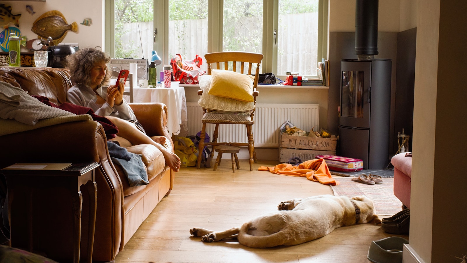 Woman on phone, with dog lying near by