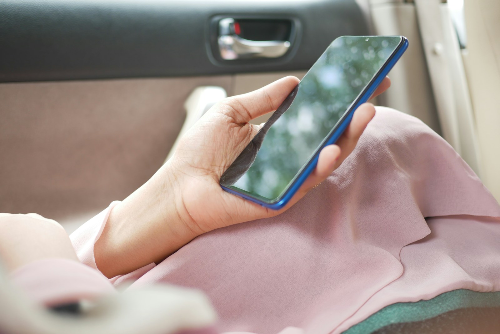 close up of women hand holding smart phone while sited in a car