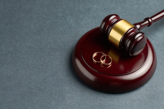 Judge gavel and wedding rings on grey background with copy space