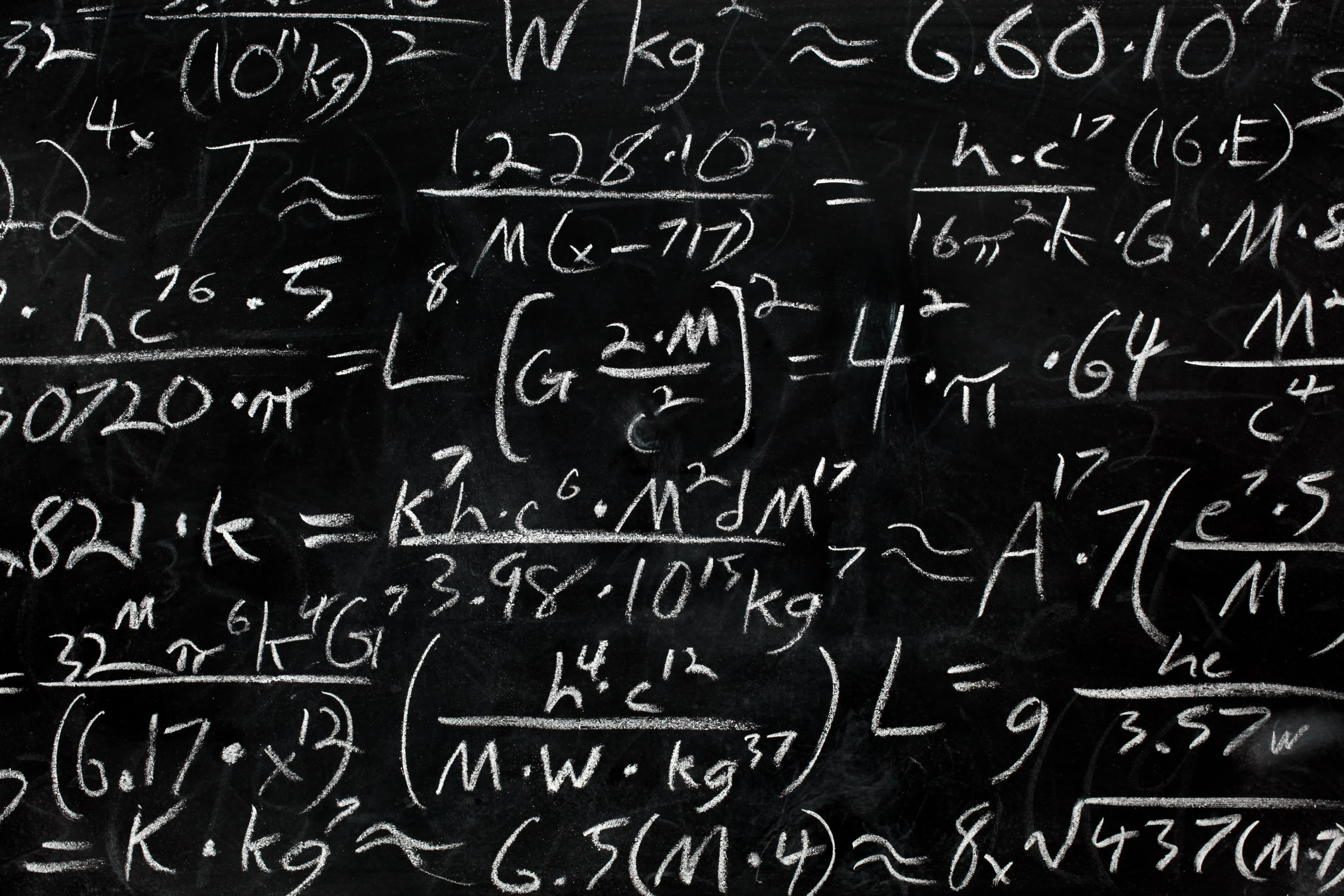Math equations and formula written in chalk on messy chalkboard