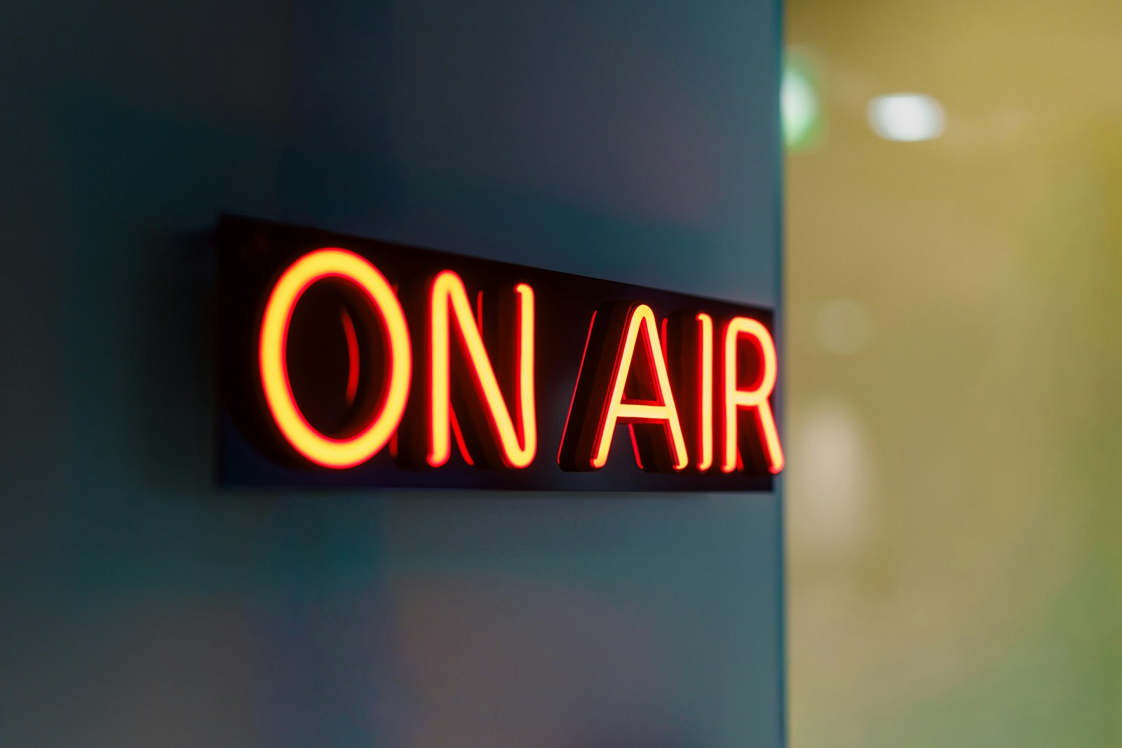 Illuminated on air sign with glowing red neon letters mounted on wall surface, symbol of live presence