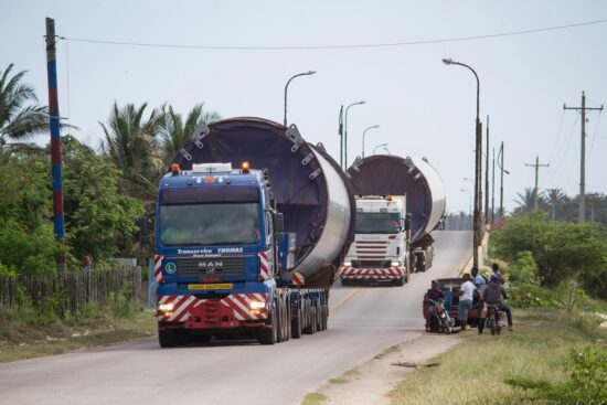 Mens from rural community watching windmills parts been transported.