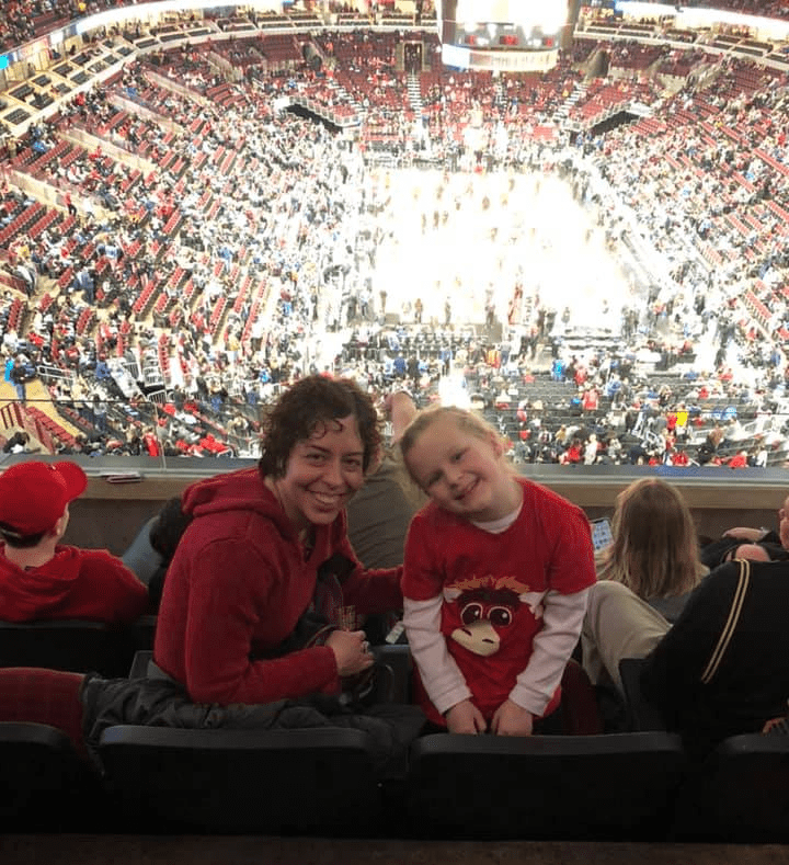 A woman and a little girl sitting in the stands with the basketball court behind them