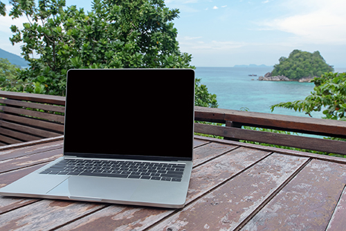 Mobile work office on the sea view terrace with blank laptop screen