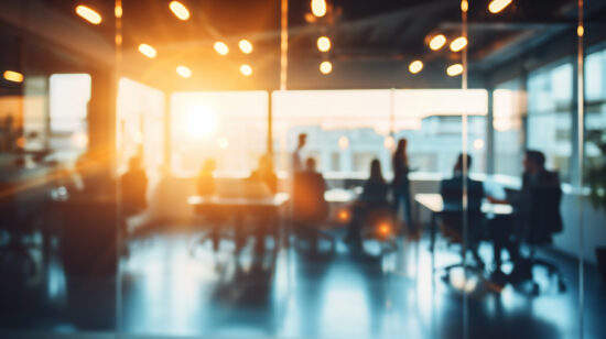 Blurred image of business people walking in modern office with sunlight.