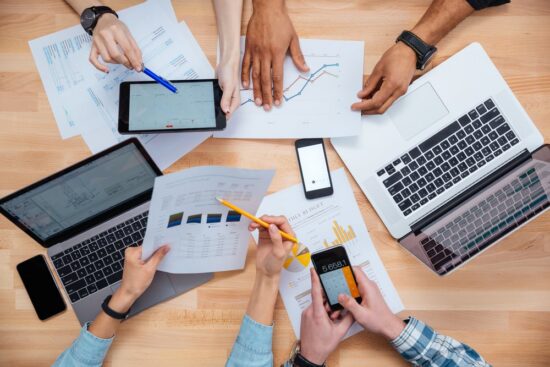 https-www-xakiatech-com-hubfs-business%20people%20using%20mobile%20phones%20and%20laptops%2c%20calculating%20and%20discussing%20charts%20and%20diagrams%20for%20financial%20report-jpeg