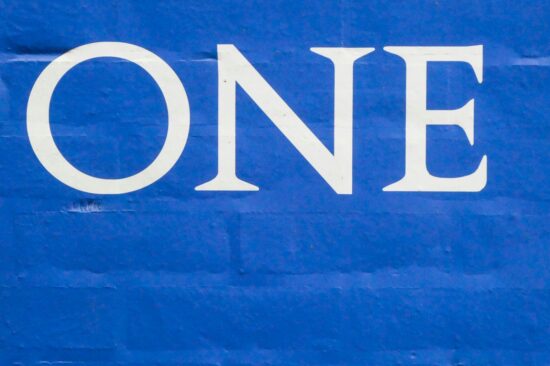 The word one in white on a blue brick wall.
